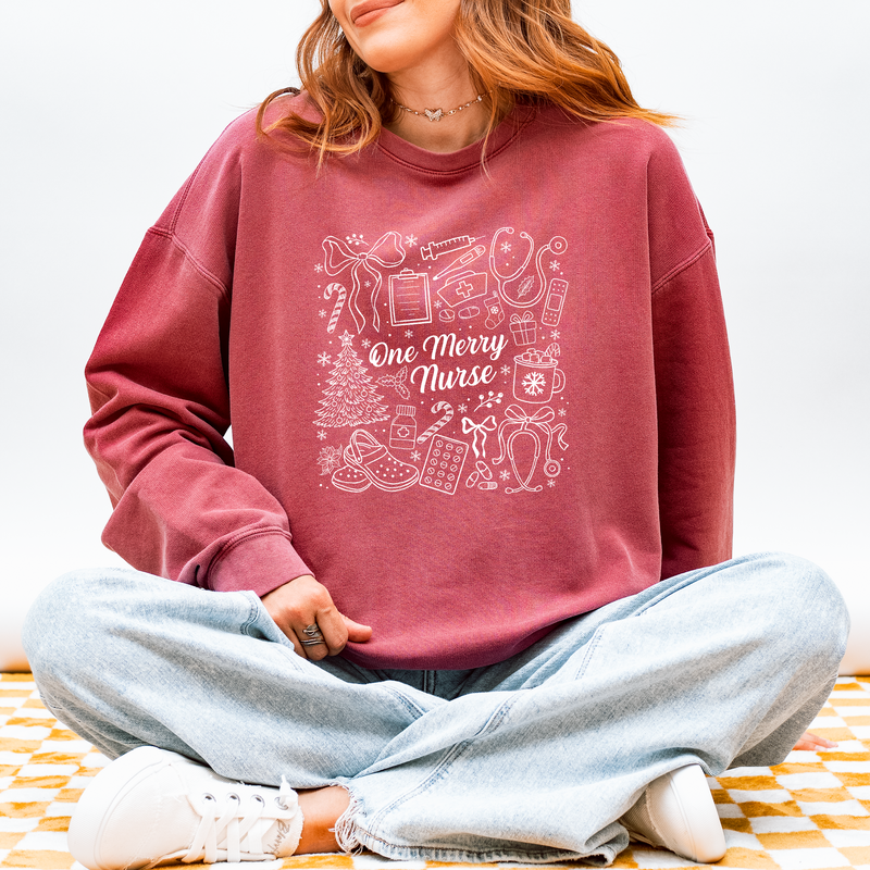 Woman wearing the One Merry Nurse Christmas sweatshirt in Crimson with hand-drawn holiday nurse doodles