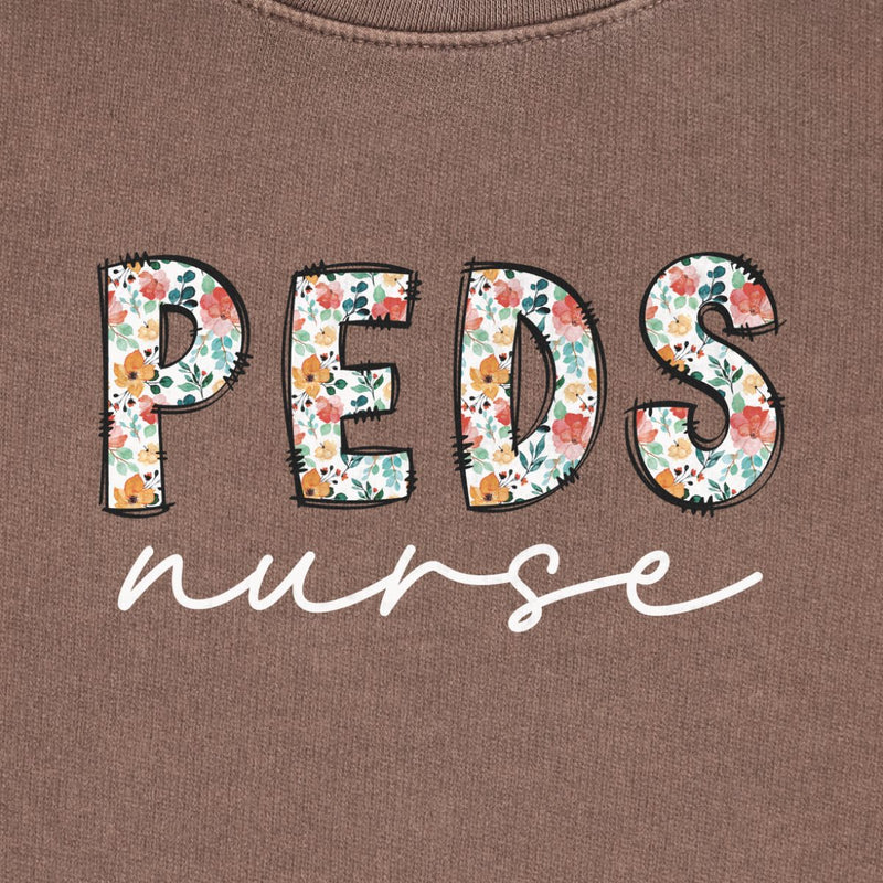Peds Nurse Floral Crewneck in Espresso, close-up of the floral "PEDS" letters with black script "nurse" print on a folded crewneck