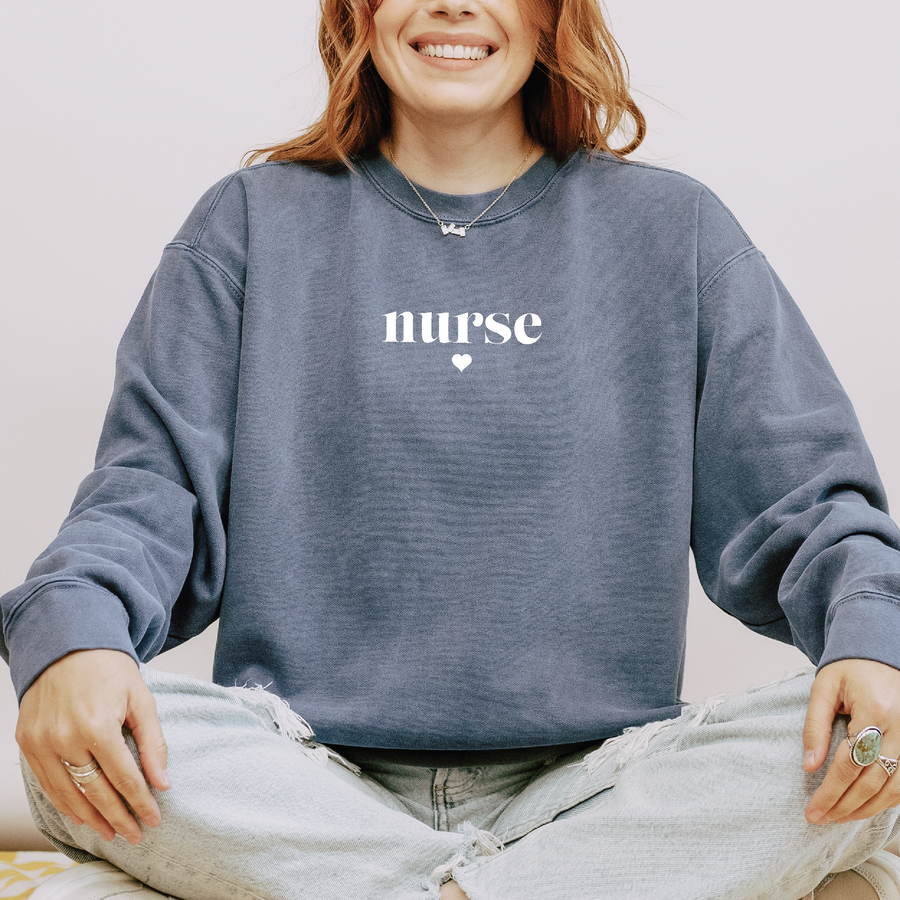 Model wearing the minimalist nurse sweatshirt with serif lettering and tiny heart