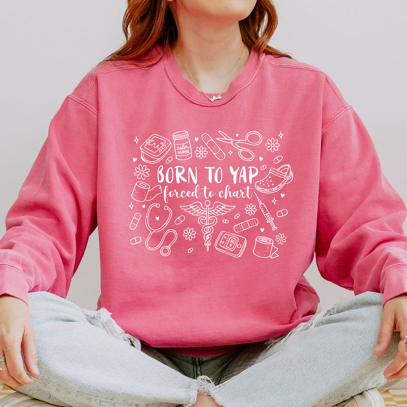 Model wearing the Born to Yap, Forced to Chart nurse sweatshirt with medical doodles
