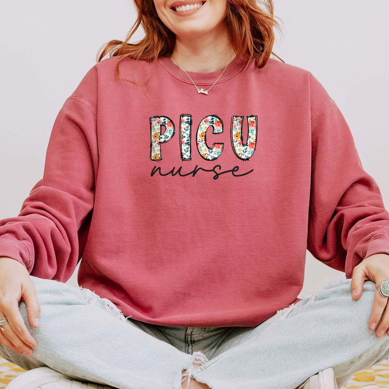 Model wearing the PICU nurse sweatshirt with floral block letters and script