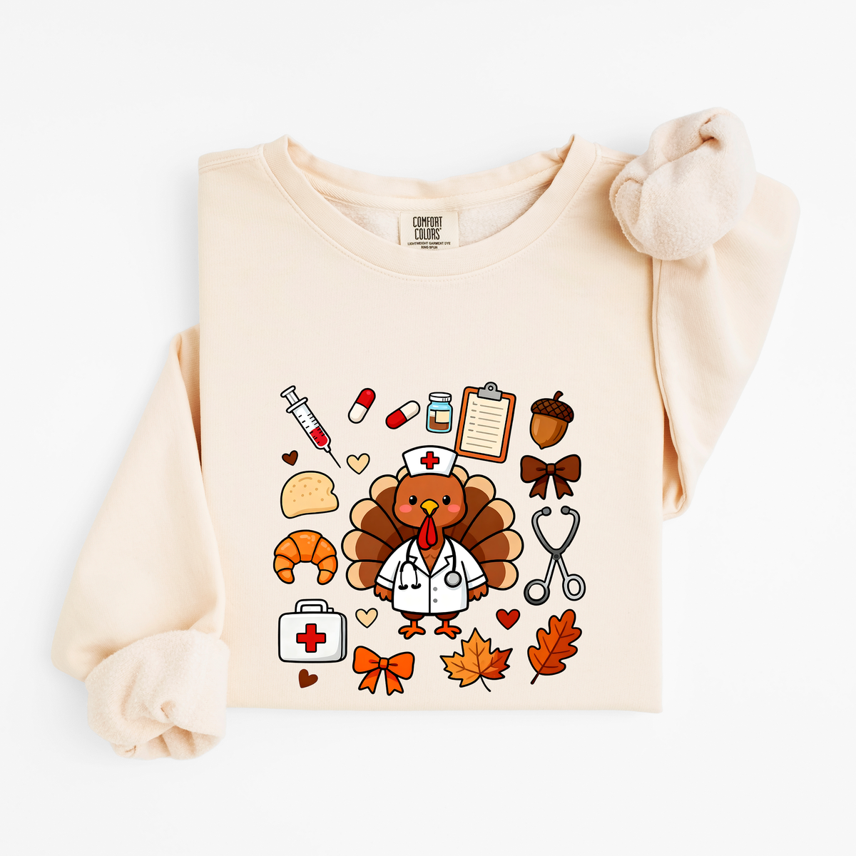 Ivory Cute Turkey Nurse Thanksgiving sweatshirt flat lay, turkey nurse in a white coat surrounded by nurse and fall icons, Comfort Colors 1466