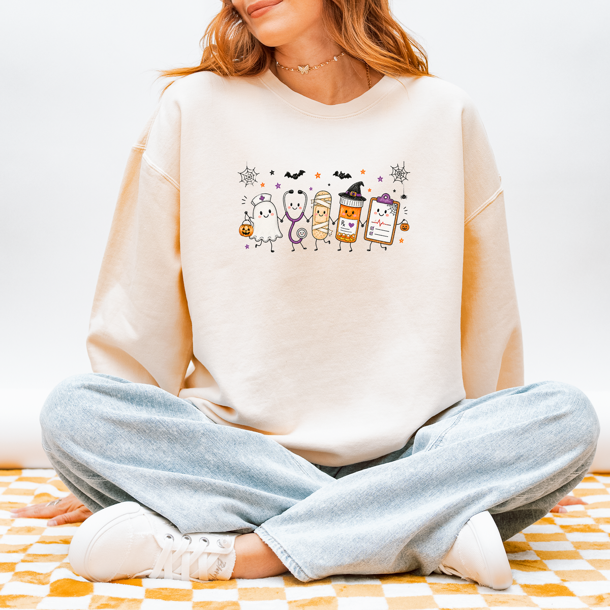 Model wearing the Halloween nurse sweatshirt with ghost nurse and smiling medical characters