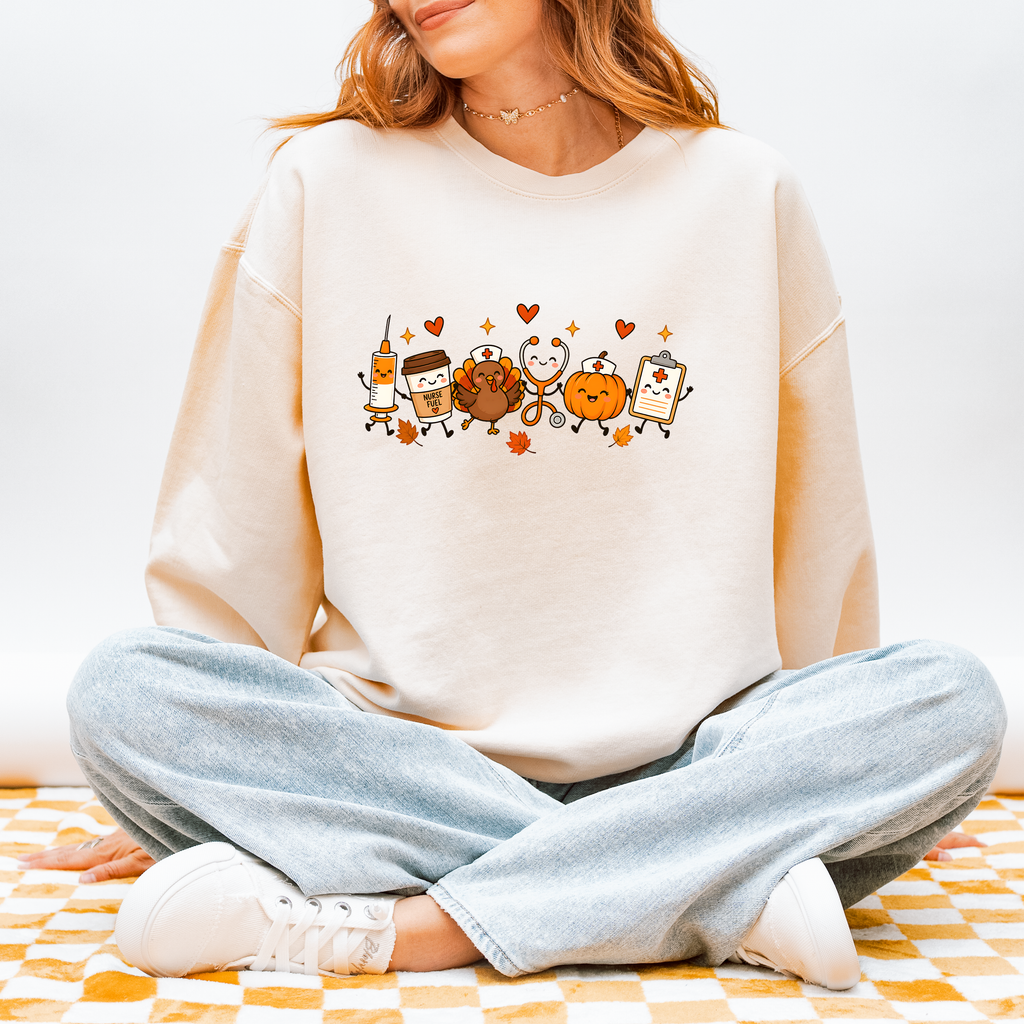 Model wearing Thanksgiving Nurse Friends sweatshirt in Ivory, front design of turkey, pumpkin, Nurse Fuel coffee, syringe, stethoscope and clipboard characters, Comfort Colors 1466