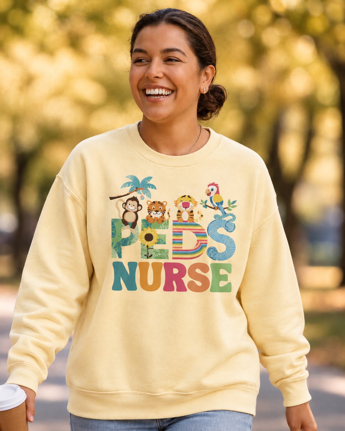 Laughing woman in a Butter Jungle Friends Peds Nurse crewneck walking through an autumn park